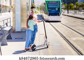 Mother and daughter waiting for the train with an electronic scooter. Mother and daughter waiting for the train with an electronic scooter.
