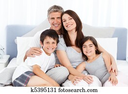 Family lying down on their bed