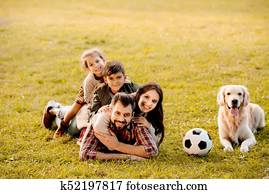 family lying in pile on grass