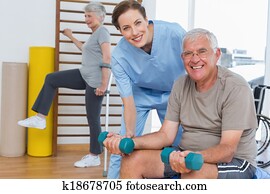 Female therapist assisting senior man with dumbbells Female therapist assisting senior man with dumbbells