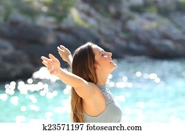 Happy woman breathing fresh air raising arms on holidays 