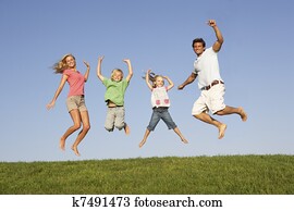 Young couple with children jump in a field