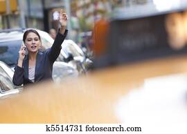 Young Woman on Cell Phone Hailing a Yellow Taxi Cab