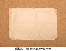 Wrinkled brown envelope attached to cork board.
