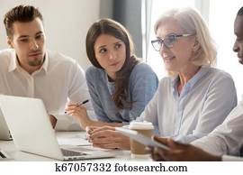 Focused young interns making notes listening to old female manager