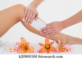 Therapist waxing woman's leg at spa center Therapist waxing woman's leg at spa center