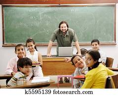 Teacher in classroom with his little happy students