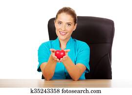 Young female doctor holding toy heart