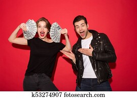 Happy punk woman showing the money while punk man posing