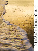 Waves lapping beach at sunset.