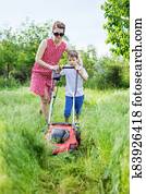 Young woman and her son mowing grass with lawn mower Young woman and her son mowing grass with lawn mower
