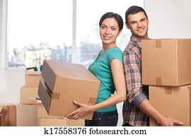 gripande, till, a, färsk, apartment., vacker, ungt par, stående, nästan, varandra, och, le, kamera, medan, holdingen, kartong kassera