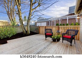 Deck with two chairs and fenced yard near home exterior shot.