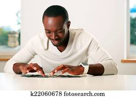 Portrait of a happy african man sitting on the table with bills of US dollars Portrait of a happy african man sitting on the table with bills of US dollars
