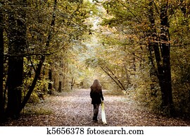 Sad woman walking alone in the woods