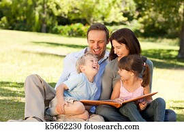 Family looking at their photo album in the park Family looking at their photo album in the park