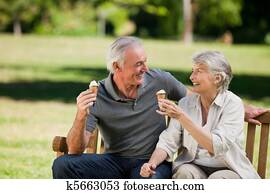 Senior couple eating an ice cream on a bench