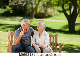 Senior couple eating an ice cream on a bench