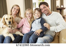 Happy young family sitting on sofa holding a dog Happy young family sitting on sofa holding a dog