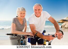 Retired couple with their bikes on the beach Retired couple with their bikes on the beach