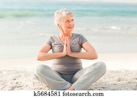 Senior woman practicing yoga on the Senior woman practicing yoga on the