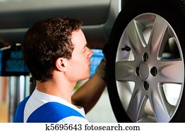 Car mechanic in workshop changing tire Car mechanic in workshop changing tire