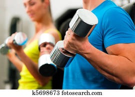 couple in gym exercising with dumbbells