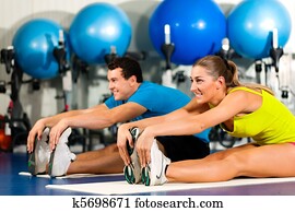 Couple in gym stretching Couple in gym stretching