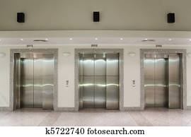 Three elevator doors in corridor of office building