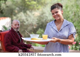 home carer serving meal to elderly man home carer serving meal to elderly man