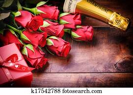 Valentine's setting with red roses, champagne and gift Valentine's setting with red roses, champagne and gift