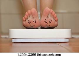 Feet on bathroom scale with hand drawn smiling cute faces Feet on bathroom scale with hand drawn smiling cute faces