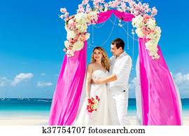 טקס של חתונה, ב, a, חוף טרופי, ב, purple., שמח, טפח, ו, כלה, מתחת, ה, קמר, קשט, עם, פרחים, ב, ה, טרופי, חול, החף., חתונה, ו, ירח דבש, concept.
