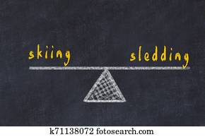 Chalk board sketch of scales. Concept of balance between skiing and sledding Chalk board sketch of scales. Concept of balance between skiing and sledding