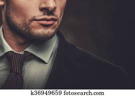 Serious well-dressed hispanic man posing on dark background.