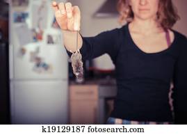 Woman holding a dead mouse in her kitchen