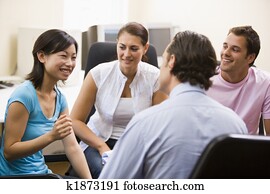 Man giving lecture to three people in computer room Man giving lecture to three people in computer room