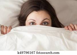 Funny surprised girl covering face with white blanket, headshot