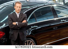 I love luxury cars. Top view of confident grey hair man in formalwear leaning at the car and looking at camera