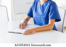 close up of doctor or nurse writing to clipboard