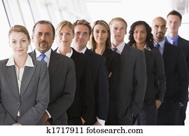 Group of co-workers standing in office space smiling (high key/depth of field)