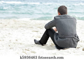A businessman sitting on the beach alone enjoying the view