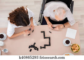 Elder Woman Playing Domino Game With Her Nurse