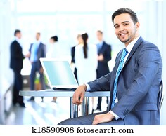 Happy young businessman using laptop in business building