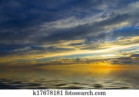 Incredible sunset, calm water and the sun, which setting in thunderclouds