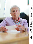 Portrait of a senior woman at home sitting at the table with papers. Shallow DOF. Portrait of a senior woman at home sitting at the table with papers. Shallow DOF.