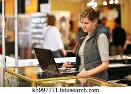 Young businesswoman using laptop computer at trade show. Young businesswoman using laptop computer at trade show.