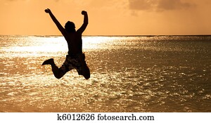 Happy Young man jumping on the beach at sunset