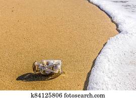 A glass bottle with shells on the seashore in the waves. A glass bottle with shells on the seashore in the waves.