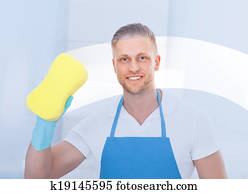 Male janitor using a sponge to clean a window